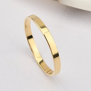 Könnte beinhalten: Ein schlichter Goldring mit einer flachen, polierten Oberfläche.