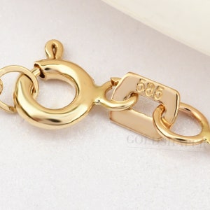 May include: Close-up of a gold chain clasp with a 585 stamp. The clasp is a lobster claw style with a round ring.