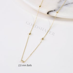 May include: A gold chain necklace with small, round balls. The balls are 2.5 mm in diameter. The chain is delicate and has a simple design.