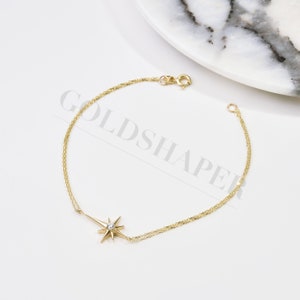 May include: A gold chain bracelet with a star charm featuring a small clear stone in the center.