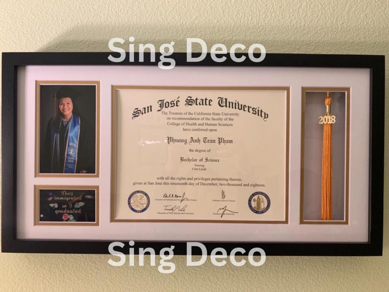 May include: A black framed diploma with a white mat and a gold seal. The diploma is from San Jose State University and is awarded to Phuong Anh Tran Pham for a Bachelor of Science degree. The diploma is dated December 11, 2018. There is a photo of the graduate in a cap and gown, a small photo of a graduation cap with the text "They immigrated so I graduated", and a gold tassel with the year 2018.