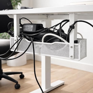 May include: A white metal under-desk cable management tray, holding a collection of black and white cables, power adapters, and other electronics. The tray is mounted beneath a white desk, with a white leg supporting the desk.