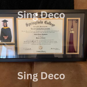 May include: A black framed diploma with a gold border and a photo of a person wearing a graduation cap and gown. The diploma is from Springfield College and is for a Master of Science degree. The diploma is dated 2019. The frame also includes a tassel with the year 2019 on it.