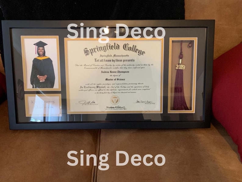 May include: A black framed diploma with a gold border and a photo of a person wearing a graduation cap and gown. The diploma is from Springfield College and is for a Master of Science degree. The diploma is dated 2019. The frame also includes a tassel with the year 2019 on it.