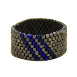Puede incluir: Un anillo de cuentas con una base gris oscuro y una franja azul.