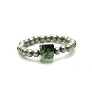 Puede incluir: Un anillo de plata con cuentas y una piedra de ágata verde musgo.