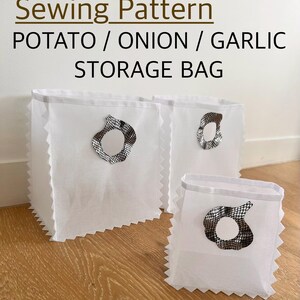 May include: Three white square storage bags with pinked edges and a circular opening on the front featuring a black and white grid pattern trim. The text Sewing Pattern POTATO / ONION / GARLIC STORAGE BAG is printed in black and brown above the bags.
