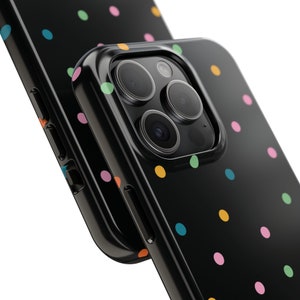 May include: A black phone case with a colourful polka dot pattern. The case has a raised camera bump with three lenses.