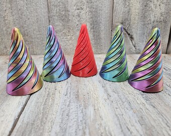May include: Five small, cone-shaped decorative objects. Four are iridescent with a swirling pattern, and one is solid red.