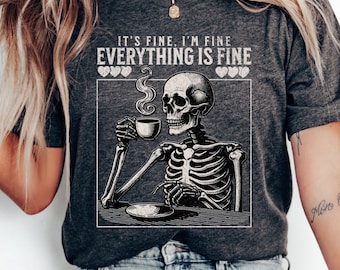 Könnte beinhalten: Ein graues T-Shirt mit einem Skelett-Motiv, das eine Tasse Kaffee hält. Der Text auf dem Shirt lautet "It's fine. I'm fine. Everything is fine." mit Herzen um den Text.