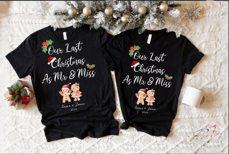 Op de afbeelding: Twee zwarte t-shirts met korte mouwen voorzien van de witte tekst Our Last Christmas As Mr & Miss, versierd met hulst, een kerstmuts en twee peperkoekfiguurtjes. Onder de figuren staan de namen Emma & Jamie en het jaartal 2026 gedrukt.