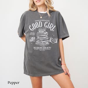 May include: Gray oversized t-shirt with a white graphic print that says "Proud Member of the Good Girl Readers Society" with a stack of books, a skull, and a heart with the text "Eyes on Me Baby".