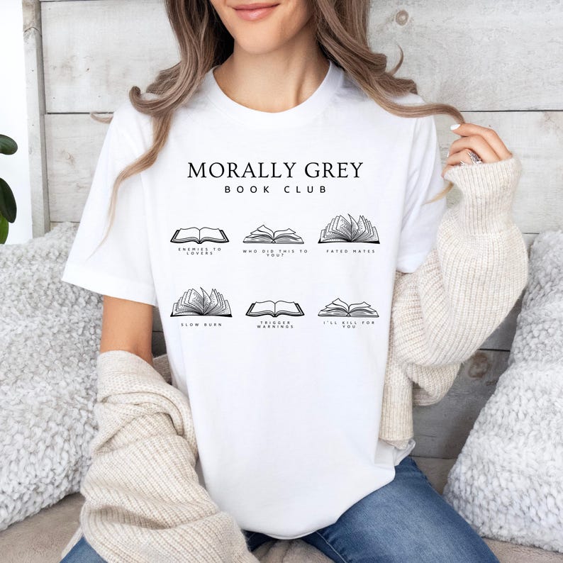 May include: White t-shirt featuring the text "MORALLY GREY BOOK CLUB" and illustrations of open books. Each book illustration has a title: "ENEMIES TO LOVERS", "WHO DID THIS TO YOU?", "FATED MATES", "SLOW BURN", "TRIGGER WARNINGS", and "I'LL KILL FOR YOU".