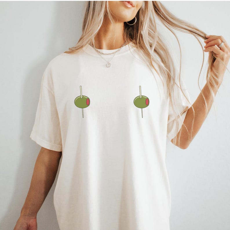 May include: A white t-shirt with a graphic of two green olives on toothpicks.