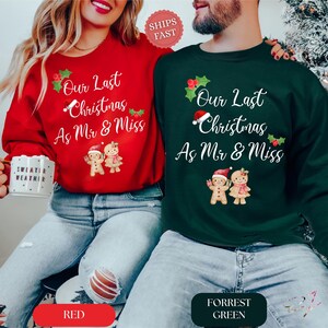Op de afbeelding: Een rood sweatshirt en een donkergroen sweatshirt, elk met de tekst Our Last Christmas As Mr & Miss, versierd met hulst, een kerstmuts en twee peperkoekmannetjes. Het rode shirt wordt gedragen met een blauwe spijkerbroek, het groene shirt ook.
