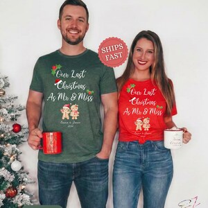 Op de afbeelding: Een donkergroen t-shirt en een rood t-shirt, beide met de witte tekst Our Last Christmas As Mr & Miss, een kerstmuts, hulstblaadjes en twee peperkoekmannetjes met de namen Emma & Jamie en het jaartal 2024 eronder gedrukt.