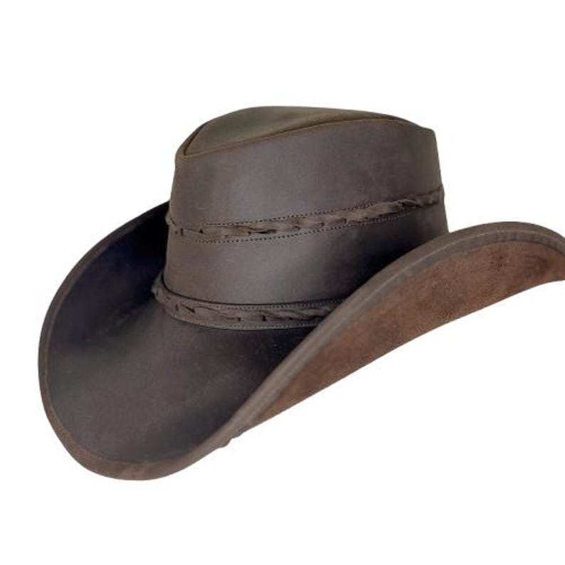 Pode incluir: Um chap&eacute;u de cowboy de couro castanho com uma banda de couro tran&ccedil;ada em torno da coroa.