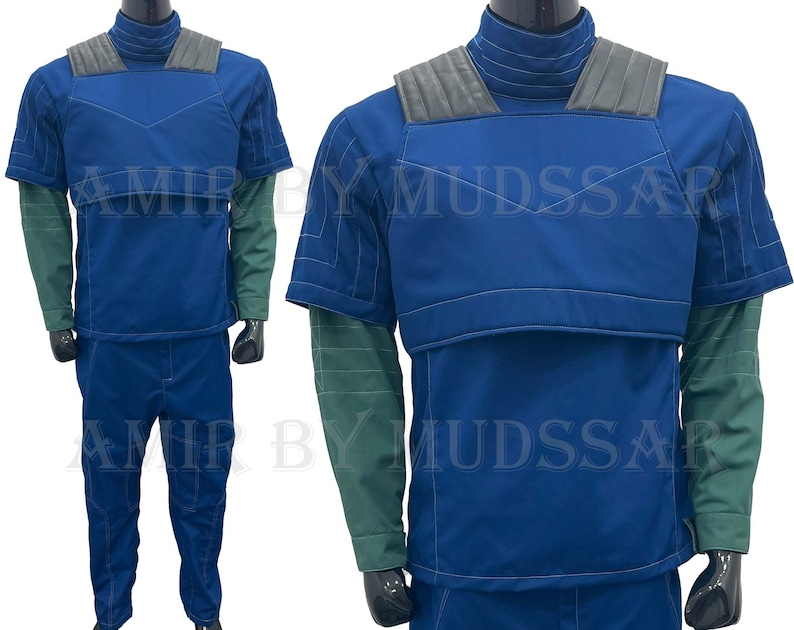 May include: A blue jumpsuit with a padded chest piece and green sleeves. The jumpsuit has a high collar and a zipper closure.