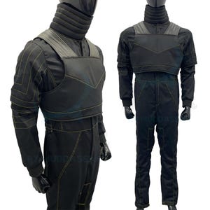 May include: Black jumpsuit with a yellow accent and a matching chest piece. The jumpsuit has a high collar and a zipper closure.
