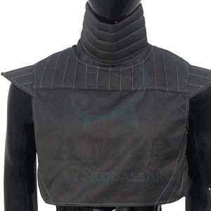 May include: A black sleeveless garment with a high collar and a quilted design. The collar has a series of horizontal lines.