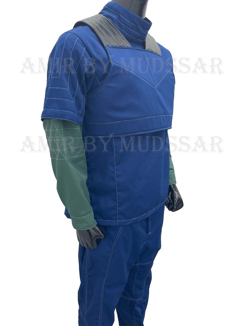 May include: A blue jumpsuit with a vest and white stitching. The vest has a gray panel across the shoulders. The jumpsuit has a high collar and short sleeves.
