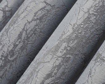 May include: Close-up of a grey textured fabric with a subtle pattern. The fabric is folded in a way that creates a series of diagonal lines.