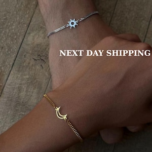 May include: Two bracelets, one silver and one gold, each with a celestial charm. The silver bracelet features a sun design, while the gold bracelet has a crescent moon. The image shows the bracelets on wrists.