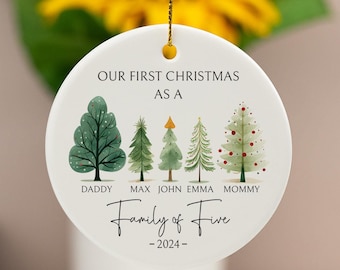 May include: White ceramic Christmas ornament with a green watercolor illustration of five Christmas trees. The trees are labeled "Daddy", "Max", "John", "Emma", and "Mommy". The ornament also says "Our First Christmas as a Family of Five - 2024 -"