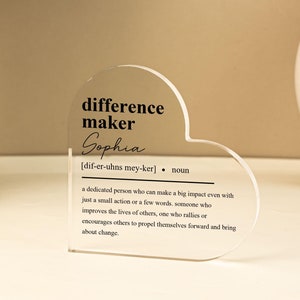 May include: A clear acrylic heart-shaped plaque with the words "difference maker" and the name "Sophia" printed in black. The plaque also includes a definition of the term "difference maker" in black text.