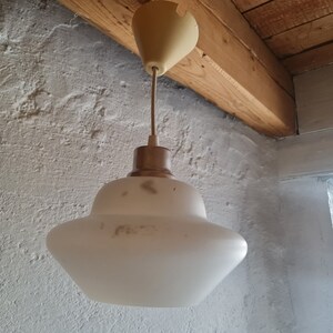 Op de afbeelding: Een witte, gematteerde glazen hanglamp met een metalen basis en een crèmekleurige plafondbevestiging.