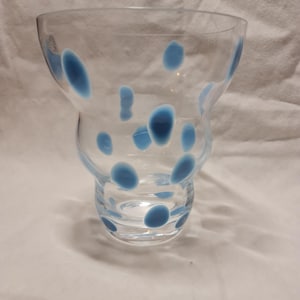 May include: A clear glass vase with a unique, wavy shape and blue polka dots.