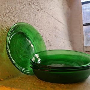 May include: A set of four green glass bowls, stacked on top of each other. The bowls are round and have a smooth, glossy finish.