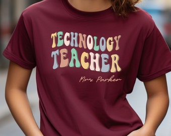 May include: A maroon t-shirt with the text "TECHNOLOGY TEACHER" in colorful, retro-style lettering. The text "Mrs. Parker" is written in a smaller font below the main text.