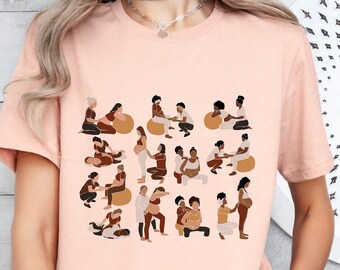 Może przedstawiać: Jasnoróżowy t-shirt z nadrukiem graficznym przedstawiającym różne ilustracje osób w różnych pozycjach, w tym siedzących, stojących i klęczących. Ilustracje są wszystkie w odcieniach brązu i czerni, a wszystkie trzymają lub dotykają duży, okrągły, brązowy przedmiot. T-shirt jest w stylu unisex i ma krótkie rękawy.