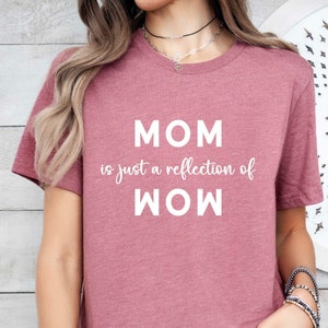 May include: A mauve t-shirt with the text "MOM is just a reflection of WOW" printed in white.