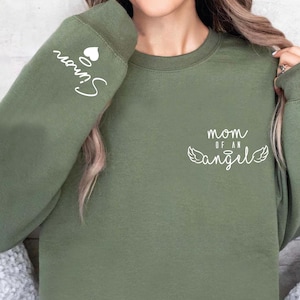 May include: A green sweatshirt with the text "Mom of an Angel" and wings on the front and the text "Sun" with a heart on the sleeve.