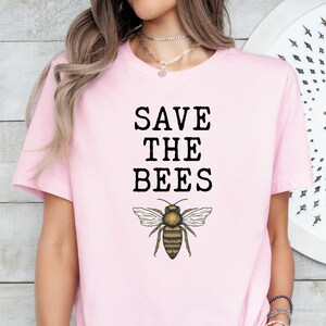 May include: Pink t-shirt with the text "SAVE THE BEES" and a graphic of a bee.