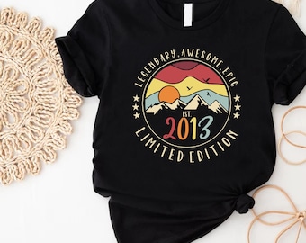 May include: Black t-shirt with a vintage-style graphic design. The graphic features a sunset scene with mountains, a sun, and the text "Legendary Awesome Epic Est. 2013 Limited Edition".