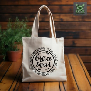 May include: A white canvas tote bag with black text that reads "Office Squad" in a circle with arrows and the words "Warm, Compassionate, Caring, Loving, Dedicated, Fun, Reliable, Loyal, Kind".