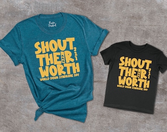 Puede incluir: Dos camisetas, una turquesa y otra negra, con el texto "Shout Their Worth" en amarillo. El texto está estilizado con una cuenta atrás de 3, 2, 1. Ambas camisetas tienen el texto "World Down Syndrome Day" debajo del texto principal.
