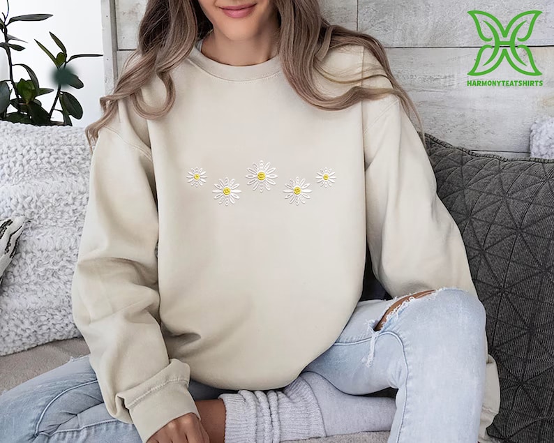 a woman sitting on a couch wearing a sweater with daisies on it