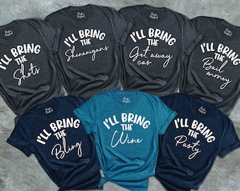 May include: Six grey and blue t-shirts with white text. Each shirt says "I'll bring the" followed by a different phrase. The phrases are "Shots", "Shenanigans", "Getaway car", "Bail money", "Bling", "Wine", and "Party".
