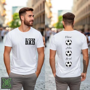 Peut inclure: T-shirt blanc avec l'inscription "SOCCER DAD" sur le devant et les noms Oliver, John et Brad avec des graphiques de ballon de football au dos. Le t-shirt est de style col rond et est fait d'une mati&egrave;re douce.