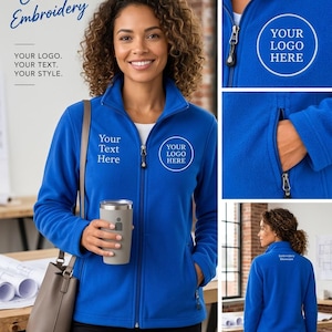 May include: A royal blue full-zip fleece jacket featuring a mock neck collar, long sleeves, and two side pockets with zippers. The jacket displays white embroidered text reading Your Text Here and Your Logo Here on the front and back.