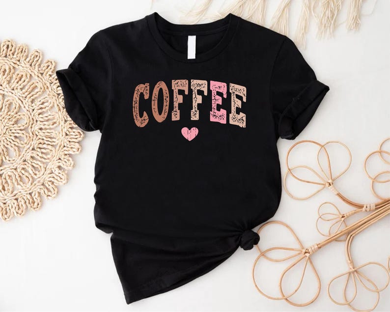 May include: Black t-shirt with the word "COFFEE" in pink, brown, and white letters with a pink heart underneath.