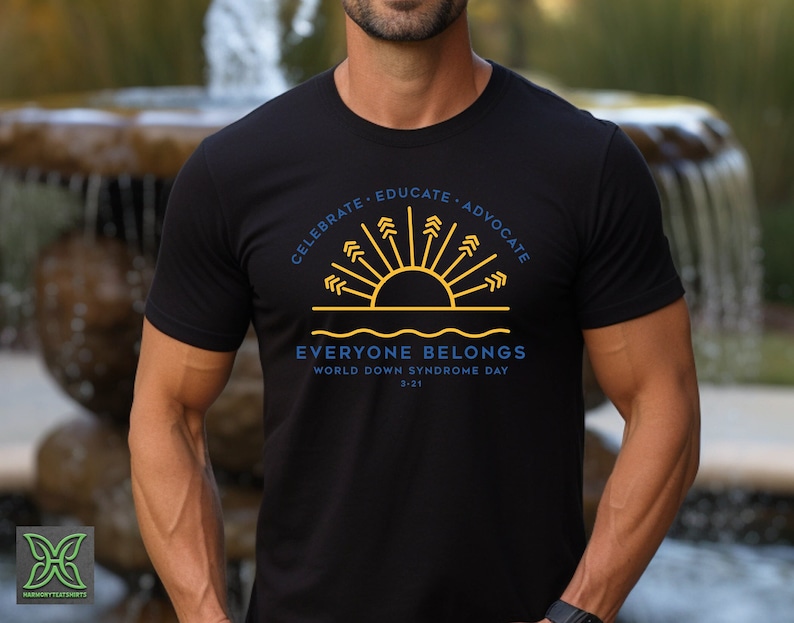 May include: Black t-shirt with a yellow sun and blue waves graphic. The text reads "Celebrate. Educate. Advocate. Everyone Belongs. World Down Syndrome Day 3-21"