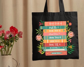 May include: Black tote bag with a design of a stack of books with floral accents. The books have titles that say "Book Title 1" through "Book Title 10".