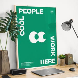 Op de afbeelding: Een groene poster met witte tekst die "Cool People Work Here" zegt en een wit oneindigheidsteken. De poster hangt aan een witte muur boven een houten bureau met een laptop, een lamp en een plant.