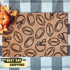 May include: A brown doormat with a pattern of black footballs and helmets. The doormat has the text "Next Day Shipping" on it.
