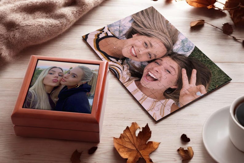 May include: Two wooden boxes with a photo of two women smiling at the camera. The photo in the smaller box is a close-up of the women, while the photo in the larger box is a wider shot of the women lying on the ground.